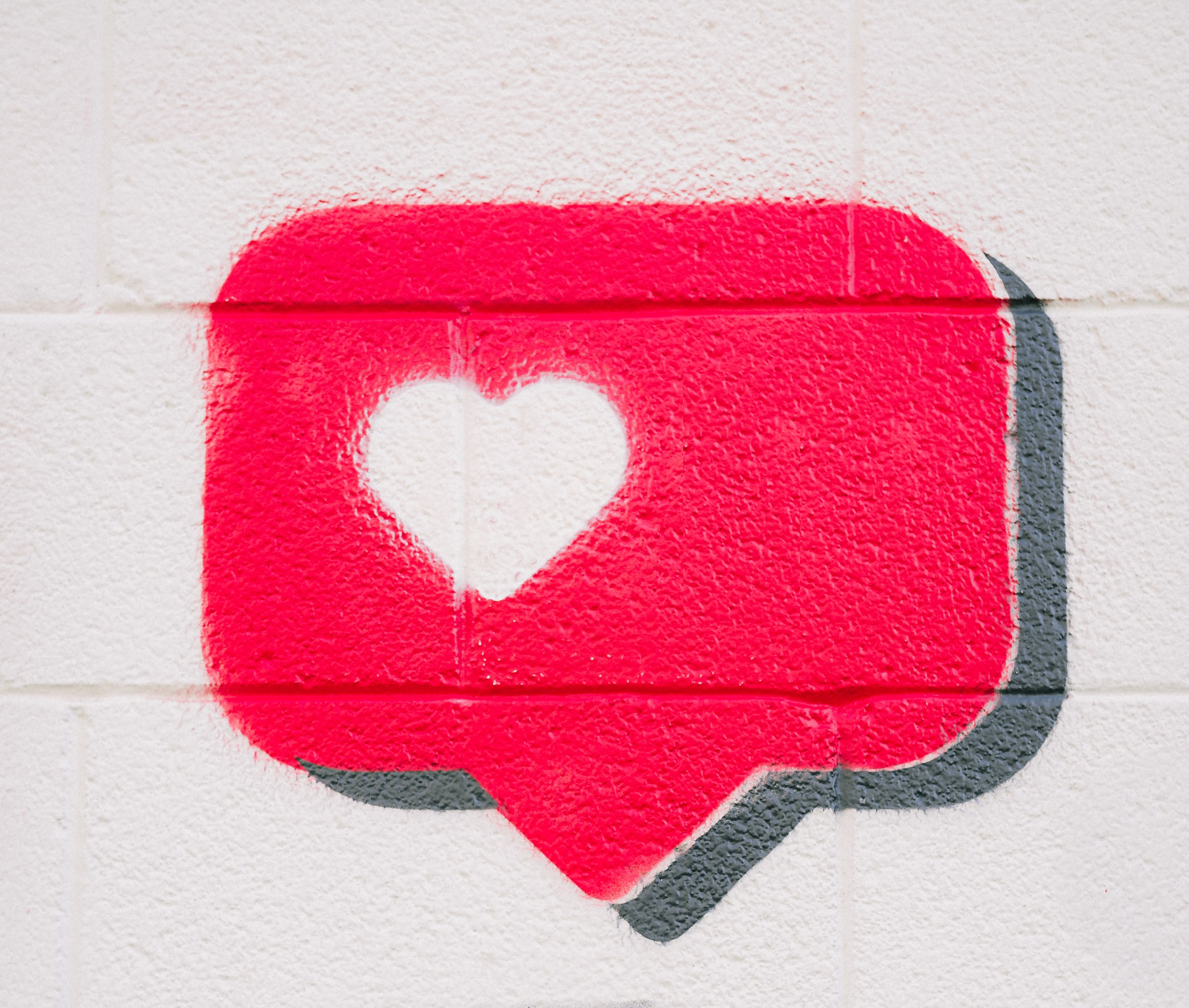 rode tekstballon met wit hartje op een muur (graffiti)