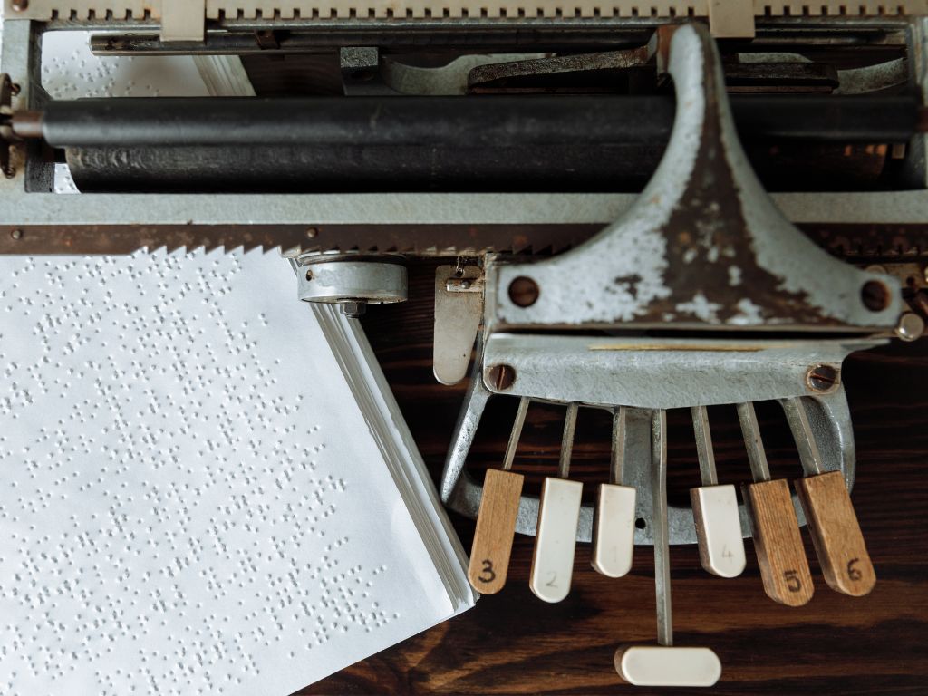 een antieke Picht braillemachine met een vel met brailletekst