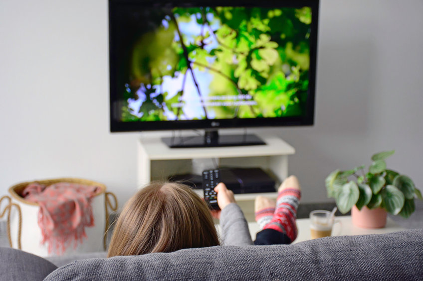 meisje wijst met afstandsbediening naar televisie