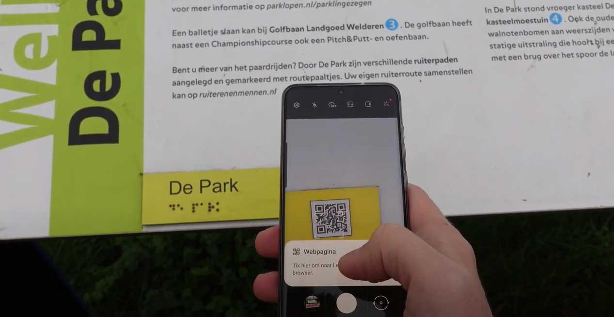 Een informatiebord bij Park Lingezegen met een brailleplaatje en een QR-code die met een smartphone wordt gescand.