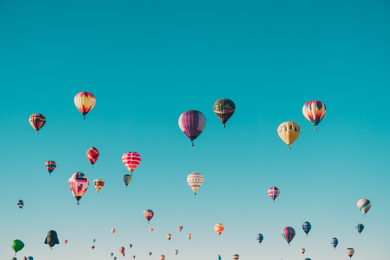 talrijke hete luchtballonnen, blauwe lucht