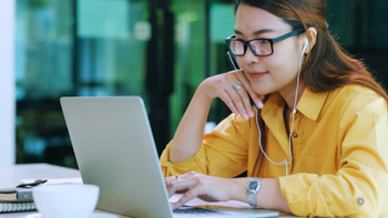 jonge vrouw met oortjes in bekijkt iets op haar laptop