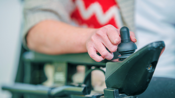 closeup van een hand die met joystick zijn rolstoel bedient