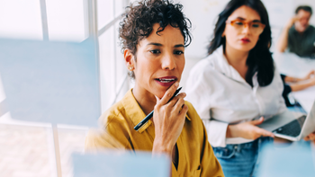 tweetal mensen in gesprek voor een board met post-it-blaadjes