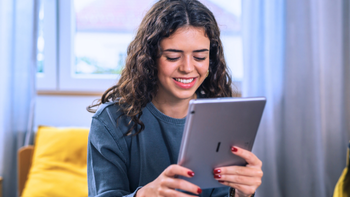 jonge vrouw bekijkt glimlachend iets op haar ipad