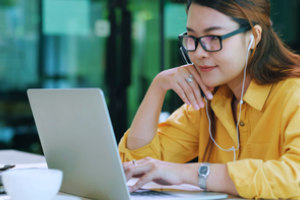 jonge vrouw met oortjes in bekijkt iets op haar laptop